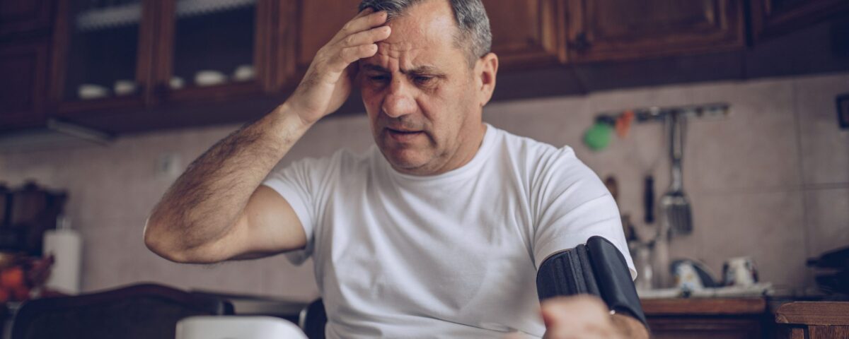 Man taking blood pressure with a hand on his head