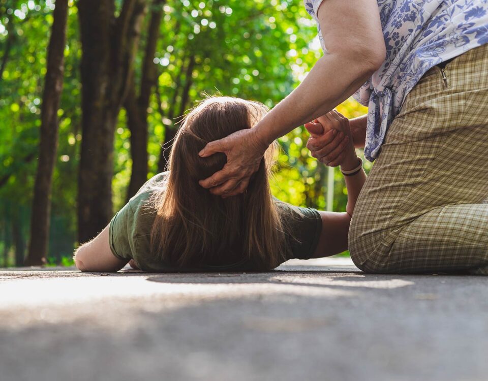 Woman holding head of a woman on the ground