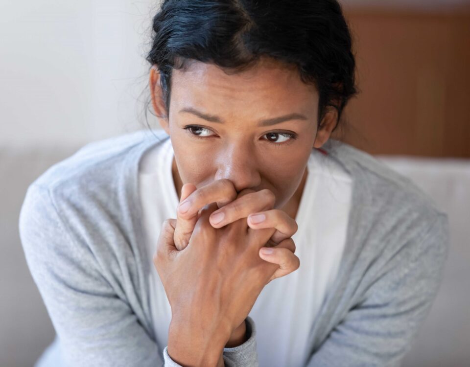 Woman looking worried with hands clasped together.