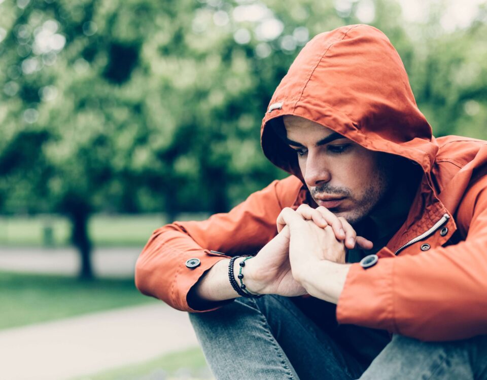 Man in an orange hoodie looking sad